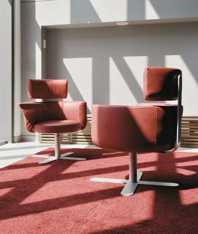 Zwei rote Stühle stehen sich gegenüber auf einem roten Teppich